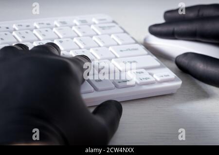 White computer keyboard and hands in black rubber gloves. Concept of crime and harassment on the web Stock Photo