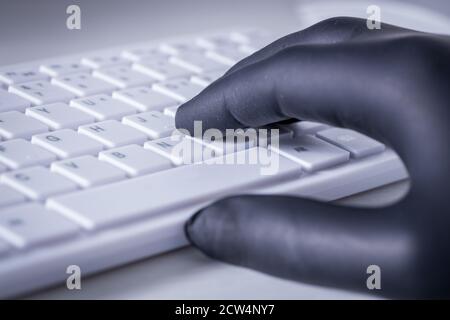 White computer keyboard and hands in black rubber gloves. Concept of crime and harassment on the web Stock Photo
