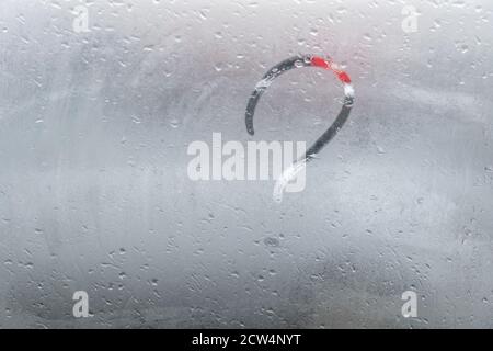 A question mark is drawn with a finger on a misted window. The question is painted on glass or on a mirror. Stock Photo