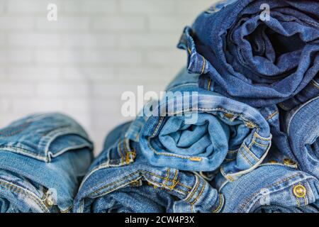 roll blue denim jeans arranged in stack on wall background. Beauty and fashion clothing concept Stock Photo