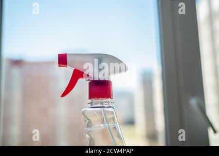 Spring cleaning at home. Window cleaning using bottle cleaners. A large plan detergent opposite the window. Outside the window is blurry Stock Photo