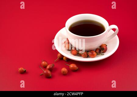 Rosehip tea in a white Cup on a red background. Stock Photo