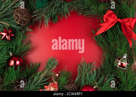 Christmas background with red toys and pine branches on a red background, top view. Stock Photo