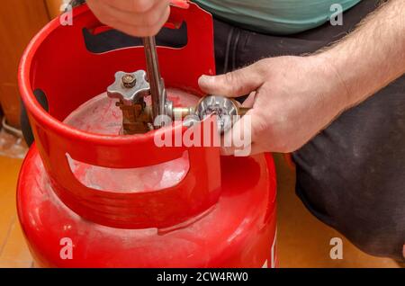 Regulator for propane-butane gas cylinder and accessories on a wooden workshop floor . Gas accessories in the workshop Stock Photo