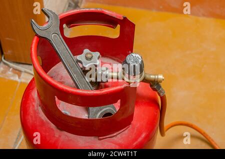 Regulator for propane-butane gas cylinder and accessories on a wooden workshop floor . Gas accessories in the workshop Stock Photo