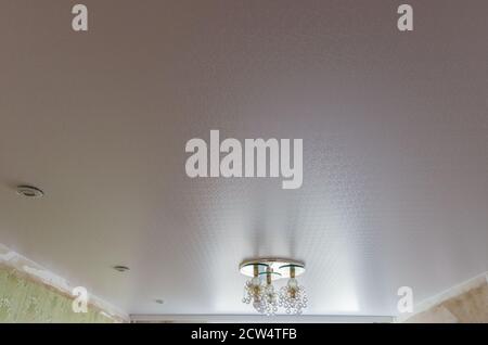 Ceiling in a room with spotlights and a chandelier mounted and turned off Stock Photo