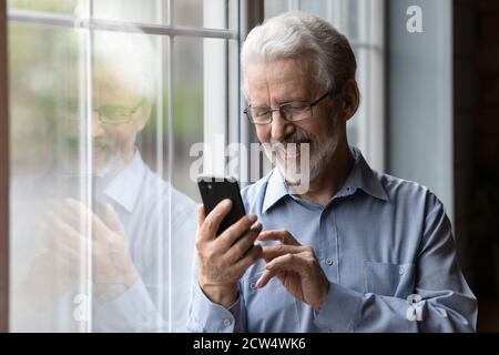 Smiling mature man using modern smartphone at home Stock Photo
