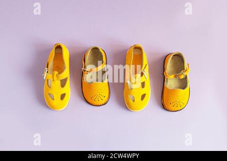 Bright yellow kids shoes on lilac background with copyspace. Baby clothes concept. Top view, flat lay Stock Photo