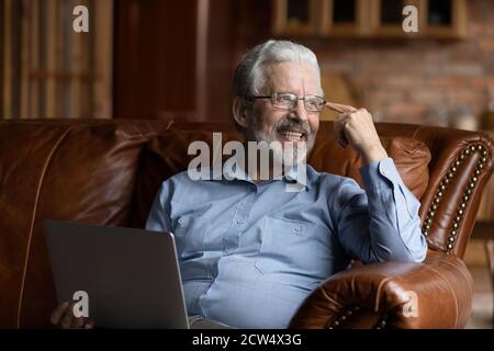 Smiling elderly man use laptop relaxing at home Stock Photo
