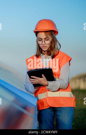 Inspector Engineer Woman Holding Digital Tablet Working in Solar Panels Power Farm, Photovoltaic Cell Park, Green Energy Concept Stock Photo