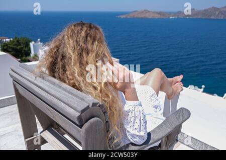 Beautiful woman in white dress sunglasses chair terrace of villa hotel Sea View Stock Photo
