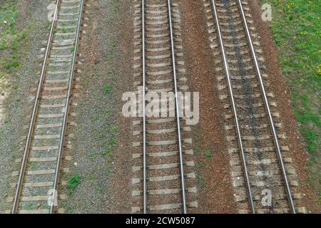 Railway tracks, top view. Brilliant iron rails and concrete sleepers in combination with powerful bolts on stony ground, with green grass on the sides Stock Photo