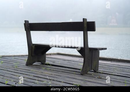 Wooden bench in the fog near the lake. Empty bench near lake. Bench near misty lake. Lonely or relax background concept Stock Photo