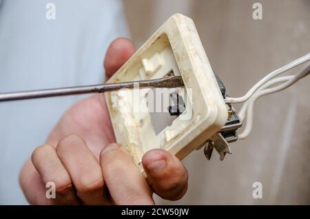 Worker man electrician is repairing damaged sockets in the apartment, installation of new closeup Stock Photo