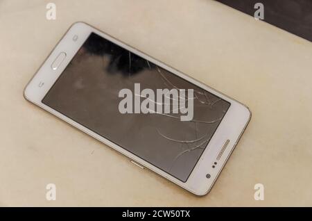Smart phone with broken screen on dark background. Close-up. Stock Photo