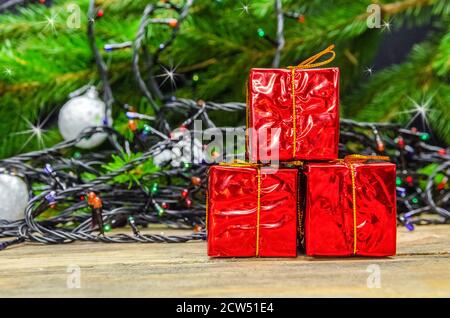 Beautiful Christmas background. Small red gift boxes on the background of a Christmas tree, garlands, Christmas balls Stock Photo