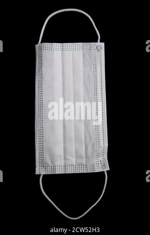 White protective face mask isolated on a black background Stock Photo