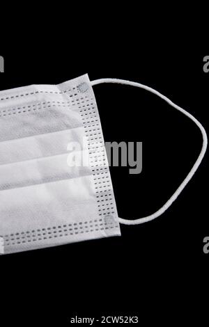 White protective face mask isolated on a black background Stock Photo