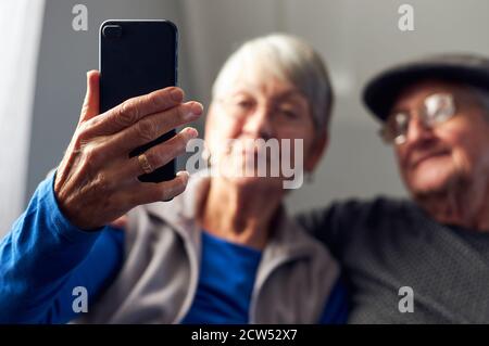 Senior Couple At Home Making Video Call To Family On Mobile Phone Stock Photo