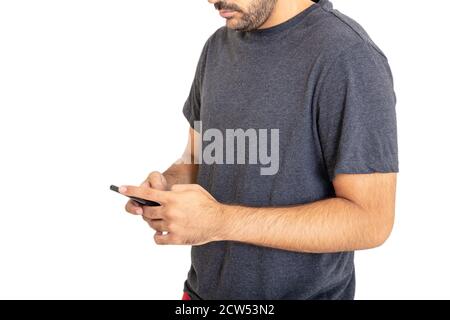 Young man wearing a blank gray t shirt lookina at his mobile phone isolated against white background. Casual male apparel, advertise template Stock Photo