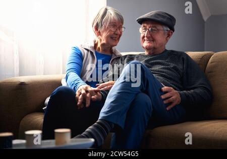 Loving Senior Couple Sitting On Sofa At Home Together Stock Photo