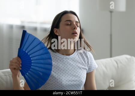 Overheated young woman wave with hand fan Stock Photo