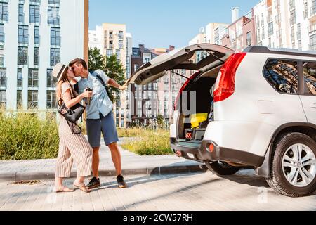 couple gathering for road trip. putting bags to car trunk Stock Photo