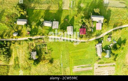 Birds eye view of group old wooden huts on mountain slope. Dirt road passes between them. Countryside, top view Stock Photo