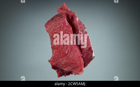 Raw beef steaks flying up in the air, isolated on grey background Stock Photo