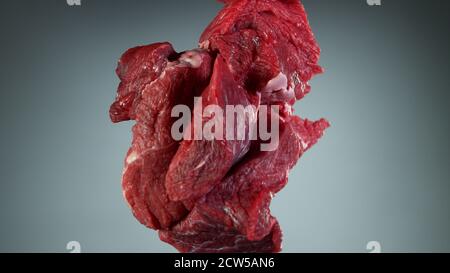 Raw beef steaks flying up in the air, isolated on grey background Stock Photo