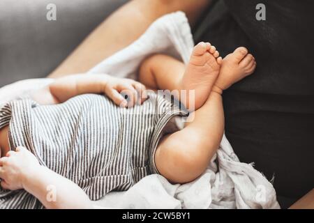Close up photo of baby's feet lying on his father while trying to sleep in a sunny day Stock Photo