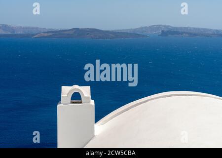 White roof with chimney on the Caldera at Oia, Santorini island, Greece. beautiful blue seascape with volcano in the background Stock Photo