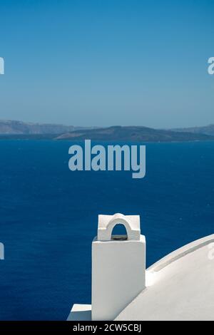 White roof with chimney on the Caldera at Oia, Santorini island, Greece. beautiful blue seascape with volcano in the background Stock Photo