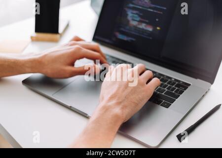 Young man mobile developer, programmer writes program code on a laptop Stock Photo