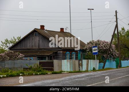 An old wooden village house stand behind a wooden palisade. Stock Photo