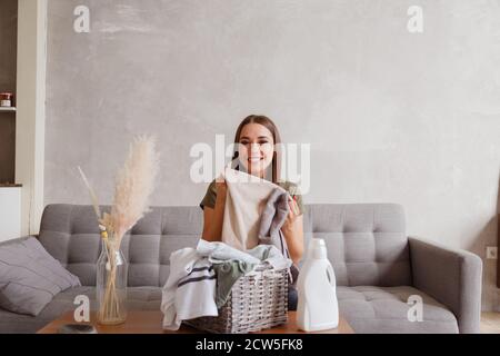 Girl enjoys clean and smelling towels after washing with new detergent gel Stock Photo