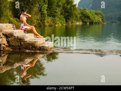beautiful woman sitting next to the river Li in Yangshuo Stock Photo