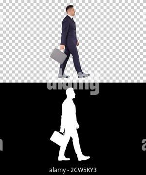 Handsome businessman in a suit walks with a briefcase, Alpha Cha Stock Photo