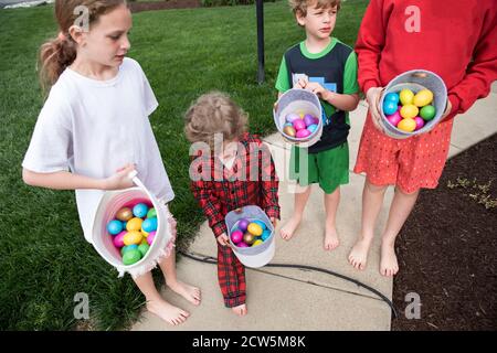 Candid Image of Four Siblings In Pajamas Outside Holding easter Basket Stock Photo