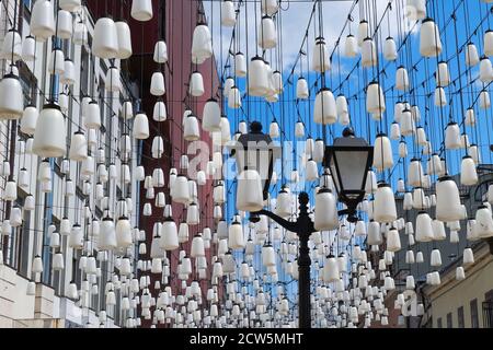 Vintage classical street lantern with white glass shades on background of decorative composition of white contemporary street lights.  Stock Photo