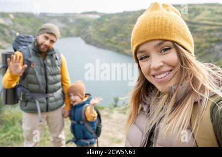 Happy young blond woman with toothy smile making selfie with her family Stock Photo
