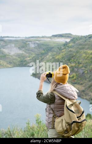 Rear view of female backpacker hiking through a rocky path beside a ...