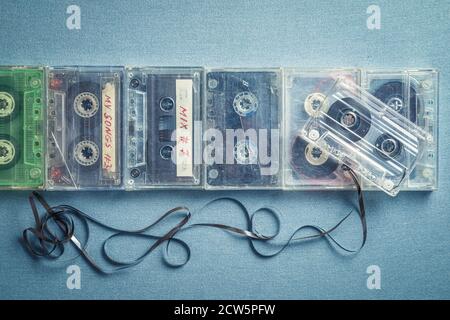Several old audio cassettes with an extracted tape on blue table Stock Photo