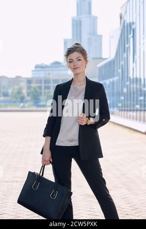 Young elegant business lady in smart casualwear holding black leather handbag Stock Photo