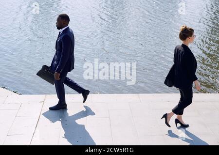 Contemporary business people in formalwear passing by each other by eiverside Stock Photo