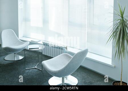 Two comfortable armchairs surrounding small round table with business documents Stock Photo