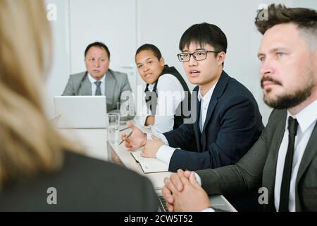 Young Asian businessman in formalwear questioning business coach at seminar Stock Photo