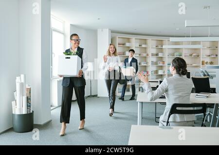 Group of young happy intercultural colleagues with boxes returning to work Stock Photo