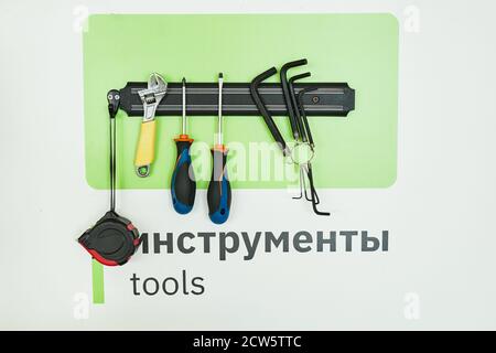 Background image of magnetic tool rack with wrenches and screwdrivers over word TOOLS written in English and Russian Stock Photo