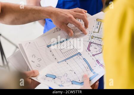 The female customer holds the layout of the house and shows it to the builders. Close-up Stock Photo